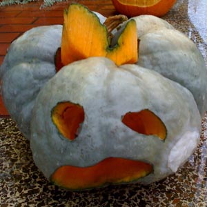 second face of jack o lantern carved into strangely lobed winter squash
