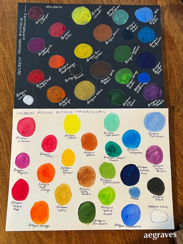 Two sheets of watercolor paper, one black, one white, with circles of Holbein Irodori watercolors painted upon them to show saturation and opacity.