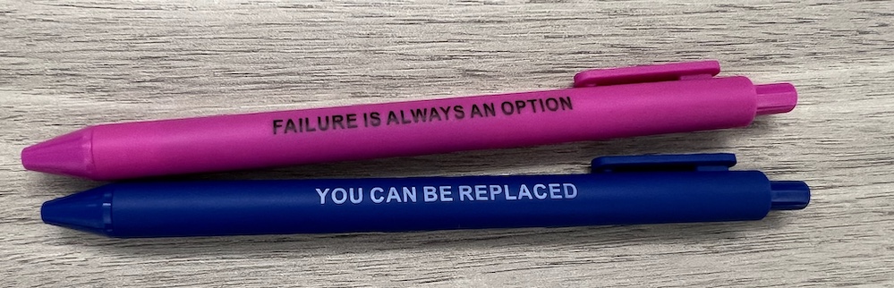 Novelty pens labeled "failure is always an option" and "you can be replaced"