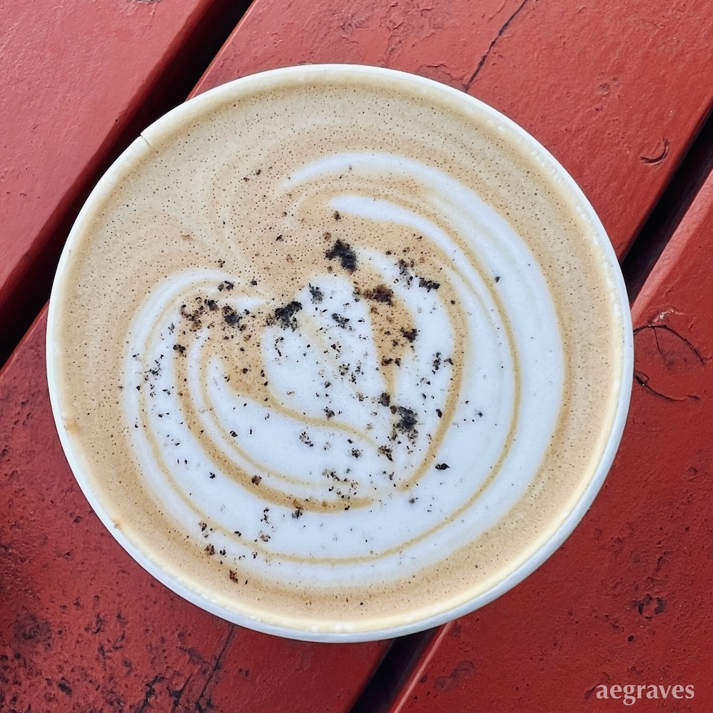 view from above of a Blue Bottle black cardamom almond milk latte on a red picnic bench